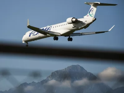 Ljubljana, Slovenia - September 15, 2019: Small Adria Airways passenger plane flying low on a clear sky sunny day with mountains in the background