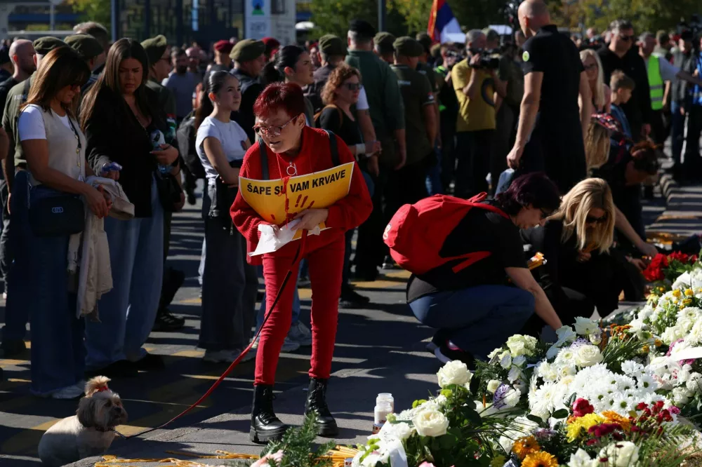 A woman holds a sign that reads: "Your paws are bloody", as people gather outside the Novi Sad railway station to pay their respects and mark the first anniversary of the fatal November 2024 railway station canopy collapse, which killed 16 people, triggering nationwide accusations of widespread corruption and negligence, in Novi Sad, Serbia, November 1, 2025. REUTERS/Zorana Jevtic