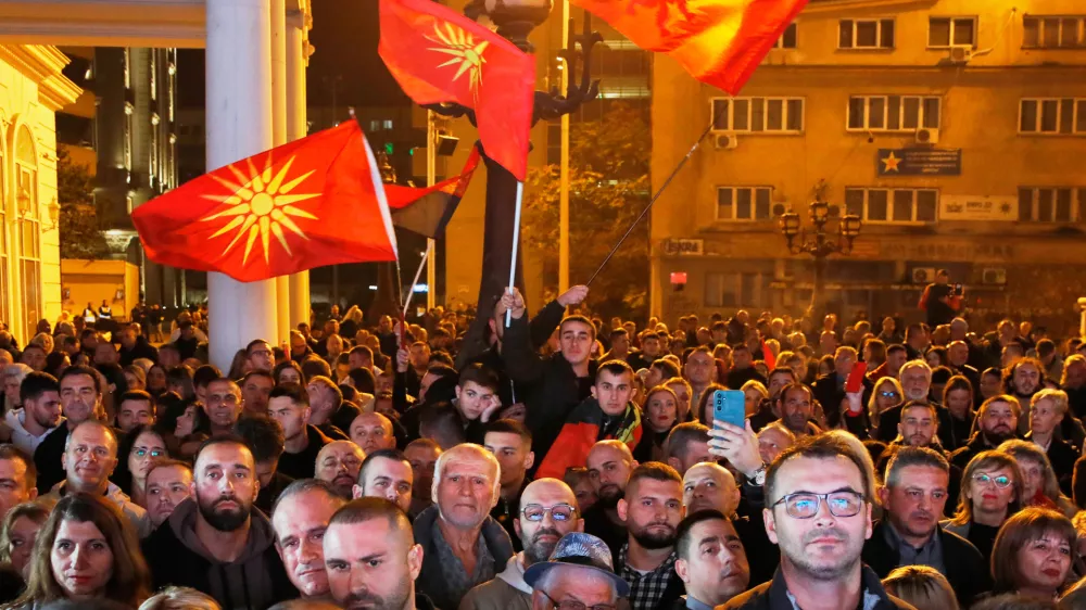 Supporters of the conservative VMRO-DPMNE party wave party flags and the old national flag as the leader Hristijan Mickoski announces a "great" victory in the local elections, at the party headquarters in Skopje, North Macedonia, on Sunday, Nov. 2, 2025. (AP Photo/Boris Grdanoski)