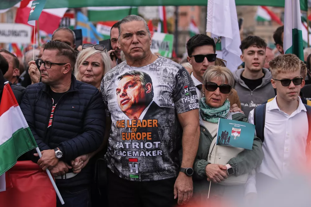 A man wearing a T-shirt with Hungarian Prime Minister Viktor Orban attends a pro-government march during celebrations marking the 69th anniversary of the outbreak of Hungary's 1956 revolution against communist rule and the Soviet Union, in Budapest, Hungary, Thursday, Oct. 23, 2025. (AP Photo/Rudolf Karancsi)