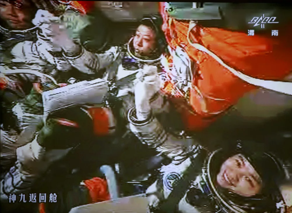 In this image made off the monitor screen at the Beijing Aerospace Flight Control Center and released by China's Xinhua News Agency, China's astronauts Jing Haipeng, center, Liu Wang, left, and Liu Yang celebrate inside the Shenzhou-9 manned spacecraft after the success of the manual docking between the spacecraft and Tiangong-1 lab module Sunday, June 24, 2012. (AP Photo/Beijing Aerospace Control Center via Xinhua) NO SALES