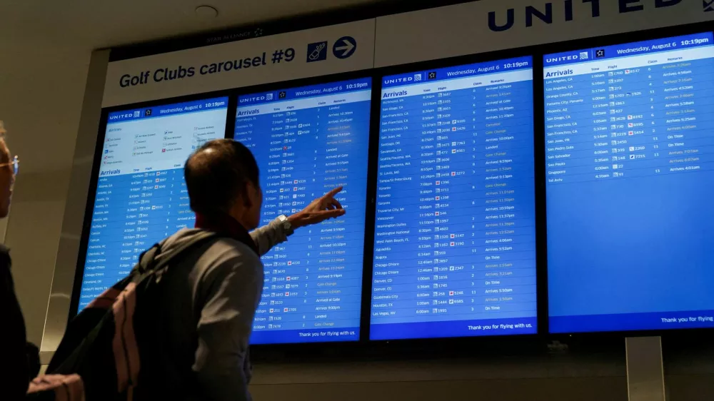FILE PHOTO: Travelers look upon a flight-arrival screen at Newark Liberty International Airport in Newark, New Jersey, U.S., August 6, 2025. REUTERS/Ryan Murphy/File Photo
