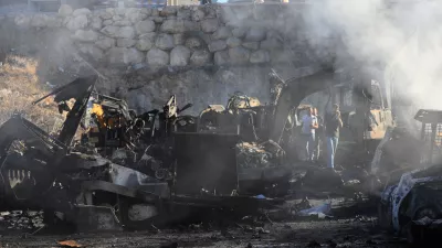 People gather at a site that sold heavy machinery, where a large number of vehicles were destroyed in Israeli airstrikes, in the southern village of Msayleh, Lebanon, Saturday, Oct. 11, 2025. (AP Photo/Mohammed Zaatari)