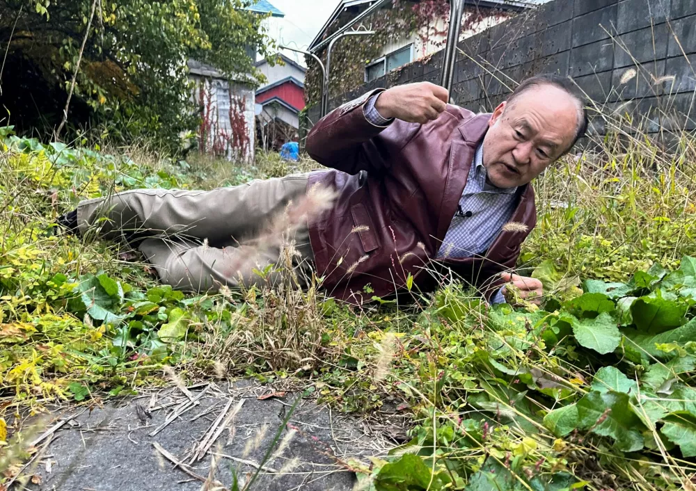 Keiji Minatoya, 68, a confectionery shop owner who was attacked by a black bear in front of the garage in his backyard on October 19, 2023, explains the situation at the time, in Kitaakita, Akita Prefecture, Japan November 6, 2025. REUTERS/Tim Kelly