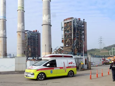 An ambulance carrying a victim leaves from the scene where a 60-meter (196-foot) tower collapsed during demolition work at a decommissioned thermal power plant in Ulsan, South Korea, Friday, Nov. 7, 2025. (Kim Keun-joo/Yonhap via AP)