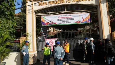 Police officers and military personnel stand guard at the gate of a school where explosions reportedly occurred, in Jakarta, Indonesia, Friday, Nov. 7, 2025. (AP Photo/Dita Alangkara)