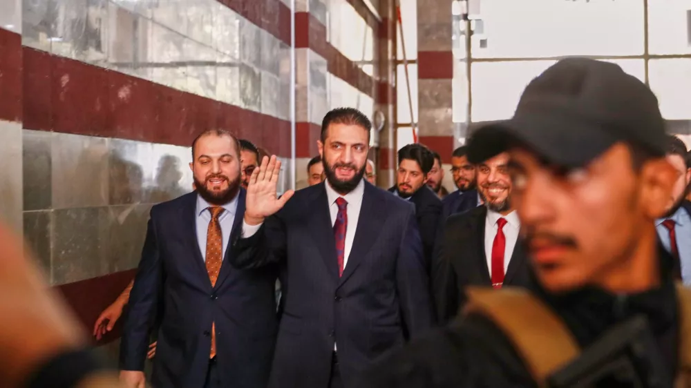 FILE - Syrian interim President Ahmad al-Sharaa waves as he enters a polling station where electoral college members are voting in a parliamentary election in Damascus, Syria, Oct. 5, 2025. (AP Photo/Omar Sanadiki, File)