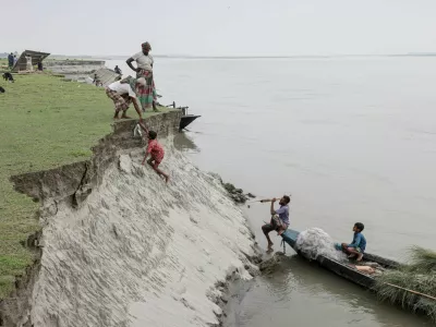 Kosim Uddin, 50, receives fish from a boy after making a purchase, on an island in the Brahmaputra River where he recently relocated his house due to erosion, in Kurigram, Bangladesh, October 29, 2025. REUTERS/Mohammad Ponir Hossain