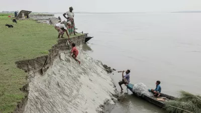 Kosim Uddin, 50, receives fish from a boy after making a purchase, on an island in the Brahmaputra River where he recently relocated his house due to erosion, in Kurigram, Bangladesh, October 29, 2025. REUTERS/Mohammad Ponir Hossain