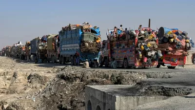 Afghan refugees sit beside trucks loaded with their belongings as they wait their turn to leave for their homeland through a border crossing point which partially opens following Oct.19 ceasefire, on the outskirts of Chaman, a border town on the Pakistan Afghan border, Wednesday, Oct. 29, 2025. (AP Photo/H. Achakzai)
