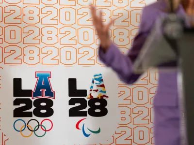 FILE - LA28 logos decorate a backdrop as First lady Jill Biden speaks at a reception at the U.S. Chief of Mission Residence to commemorate the opening of the 2024 Summer Olympics and celebrate the upcoming 2028 Olympic Games, to be held in Los Angeles, Saturday, July 27, 2024, in Paris. (AP Photo/David Goldman, File)