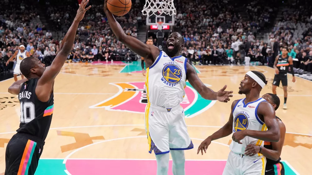 Golden State Warriors forward Draymond Green (23) grabs a rebound in front of San Antonio Spurs forward Harrison Barnes (40) during the first half of an NBA basketball game in San Antonio, Wednesday, Nov. 12, 2025. (AP Photo/Eric Gay)