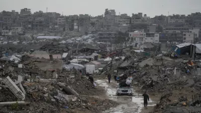 A car drives along a muddy road amid destroyed buildings in the Sheikh Radwan neighborhood of Gaza City, Friday, Nov. 14, 2025. (AP Photo/Jehad Alshrafi)