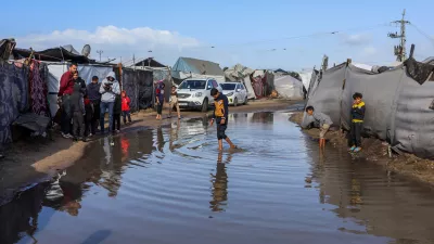 15 November 2025, Palestinian Territories, Khan Yunis: Children walk through the rainwater between their tents, as Palestinians suffer from the bitter cold and heavy rains that inundate their tents in the Al-Attar area of &middot;&middot;Mawasi, west of Khan Younis in the southern Gaza Strip. Photo: Abed Rahim Khatib./dpa
