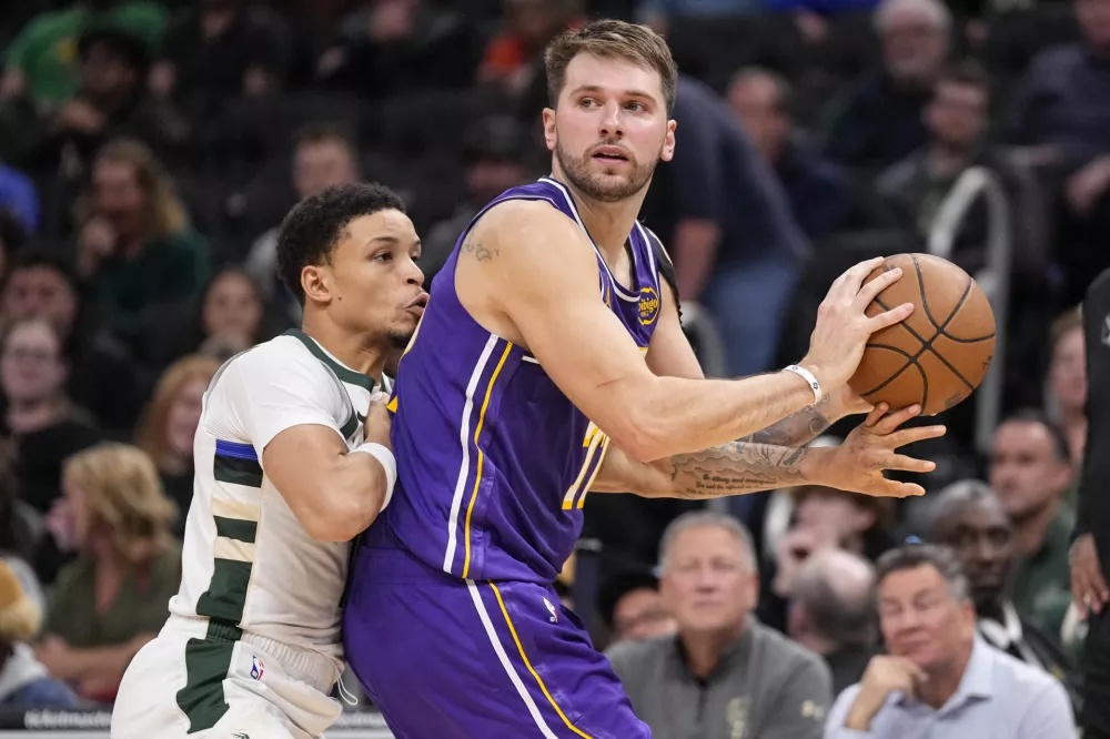 Nov 15, 2025; Milwaukee, Wisconsin, USA; Los Angeles Lakers guard Luka Doncic (77) looks to pass the ball as Milwaukee Bucks guard Ryan Rollins (13) defends during the fourth quarter at Fiserv Forum. Mandatory Credit: Jeff Hanisch-Imagn Images