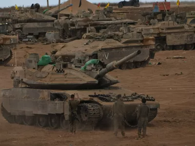 Israeli soldiers work on a tank near the Israeli-Gaza border, as seen from southern Israel, Thursday, Oct. 9, 2025, following the announcement that Israel and Hamas have agreed to the first phase of a peace plan to pause the fighting. (AP Photo/Ariel Schalit)