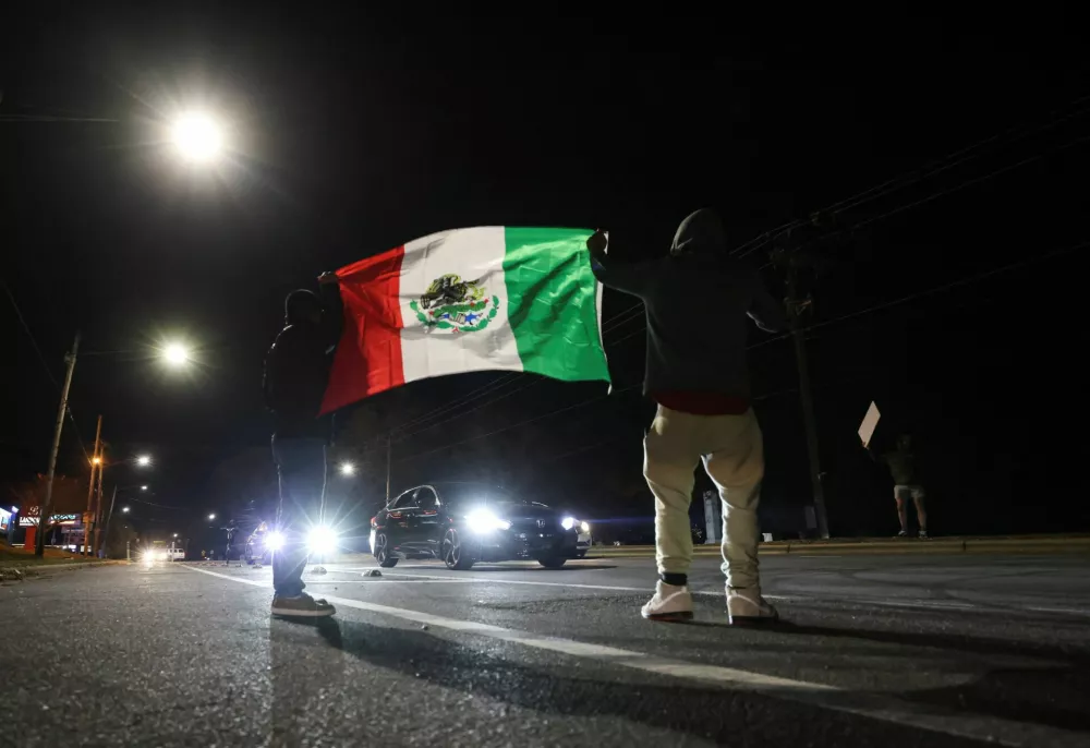 Demonstrators holding a Mexican flag participate in a protest, after federal authorities conducted raids, expanding their crackdown on illegal immigration, in Charlotte, North Carolina, U.S., November 17, 2025. REUTERS/Sam Wolfe