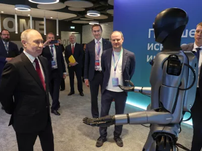 Russian President Vladimir Putin, left, looks at a humanoid robot with built-in Sberbank's GigaChat as he visits an exhibition of the AI Journey&nbsp;2025, an international conference on artificial intelligence and machine learning, at the Sberbank City business complex in Moscow, Russia, Wednesday, Nov. 19, 2025. (Vyacheslav Prokofyev, Sputnik, Kremlin Pool Photo via AP)