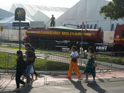People walk past as a firefighter works at the COP30 U.N. Climate Summit following a fire, Thursday, Nov. 20, 2025, in Belem, Brazil. (AP Photo/Fernando Llano)