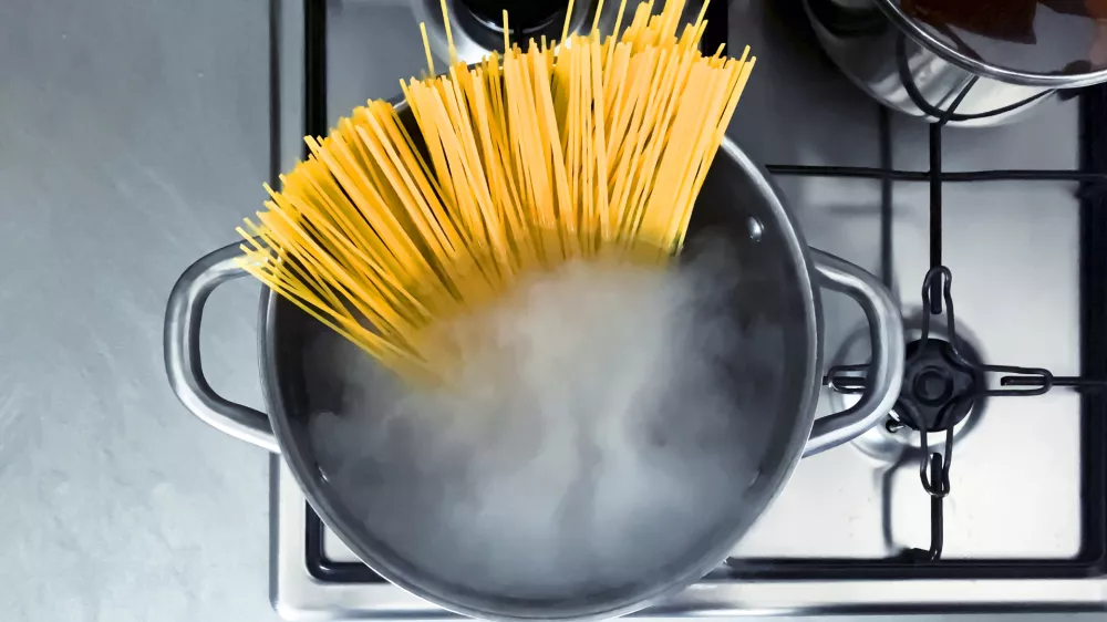 Cooking raw spaghetti in the boiling water contained in a saucepan. Italian cuisine. Raw food. interior of a domestic kitchen. Food preparation and cooking / Foto: Rarrarorro