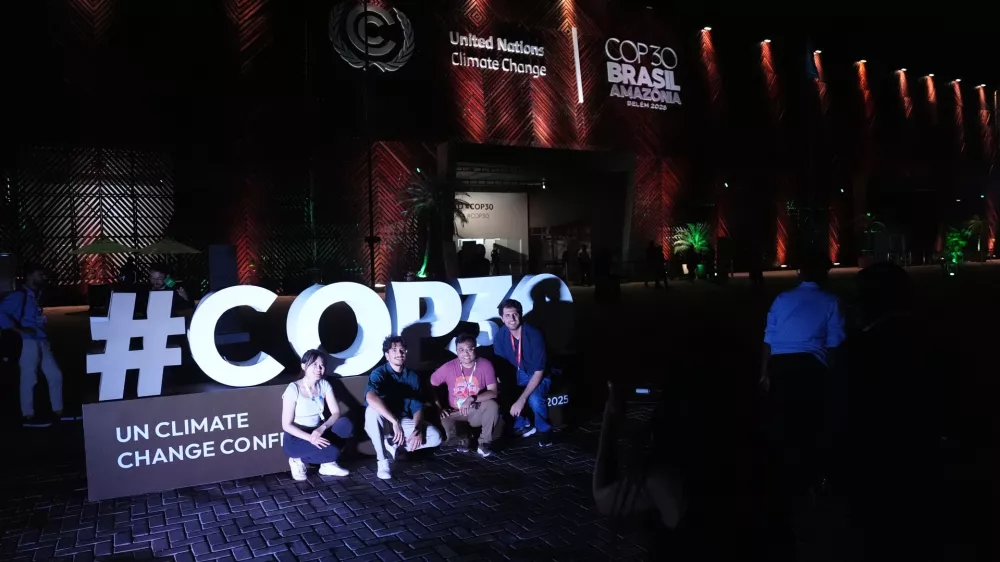 People pose for photos outside the venue for the COP30 U.N. Climate Summit, Friday, Nov. 21, 2025, in Belem, Brazil. (AP Photo/Joshua A. Bickel)