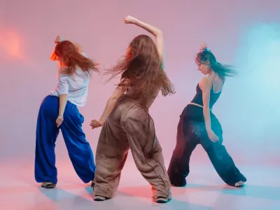 Group of young women performing jazz funk dance with expressive moves in a vibrant studio with colorful lighting and energy / Foto: Sergii Kolesnikov