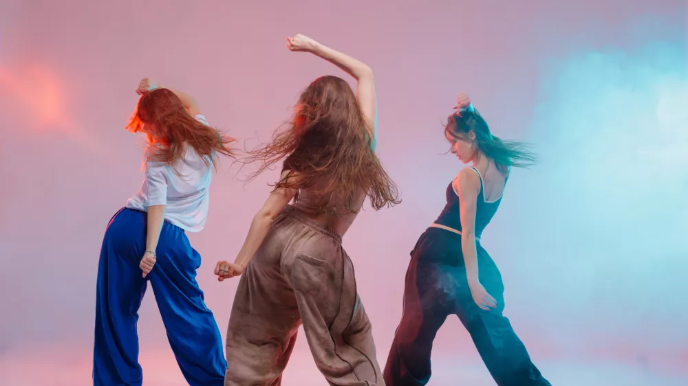 Group of young women performing jazz funk dance with expressive moves in a vibrant studio with colorful lighting and energy / Foto: Sergii Kolesnikov