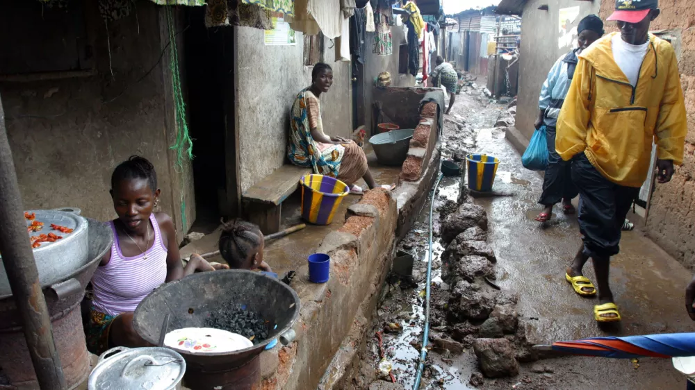 People wak through Moa Warf, a slum area in Freetown, Sierra Leone, June 3, 2004. REUTERS/Luc Gnago LG/CRB
