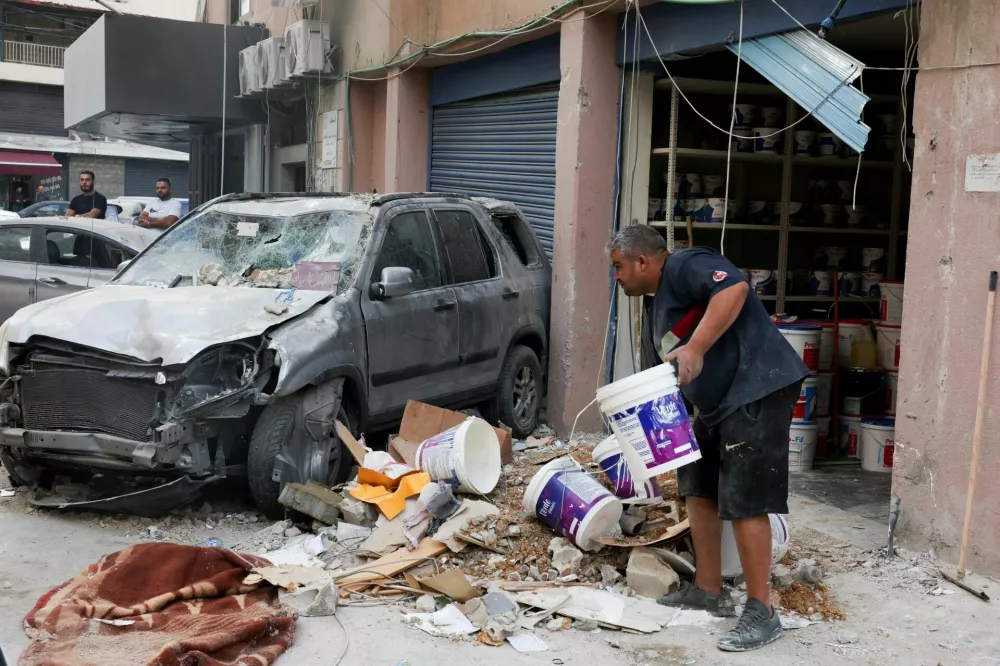 A man stands near a damaged vehicle near the site of an Israeli strike that happened yesterday on a building, after what the Israeli military said was an airstrike that killed Hezbollah's top military official, following a U.S.-brokered truce a year ago, in Beirut's southern suburbs, Lebanon November 24, 2025. REUTERS/Mohamed Azakir