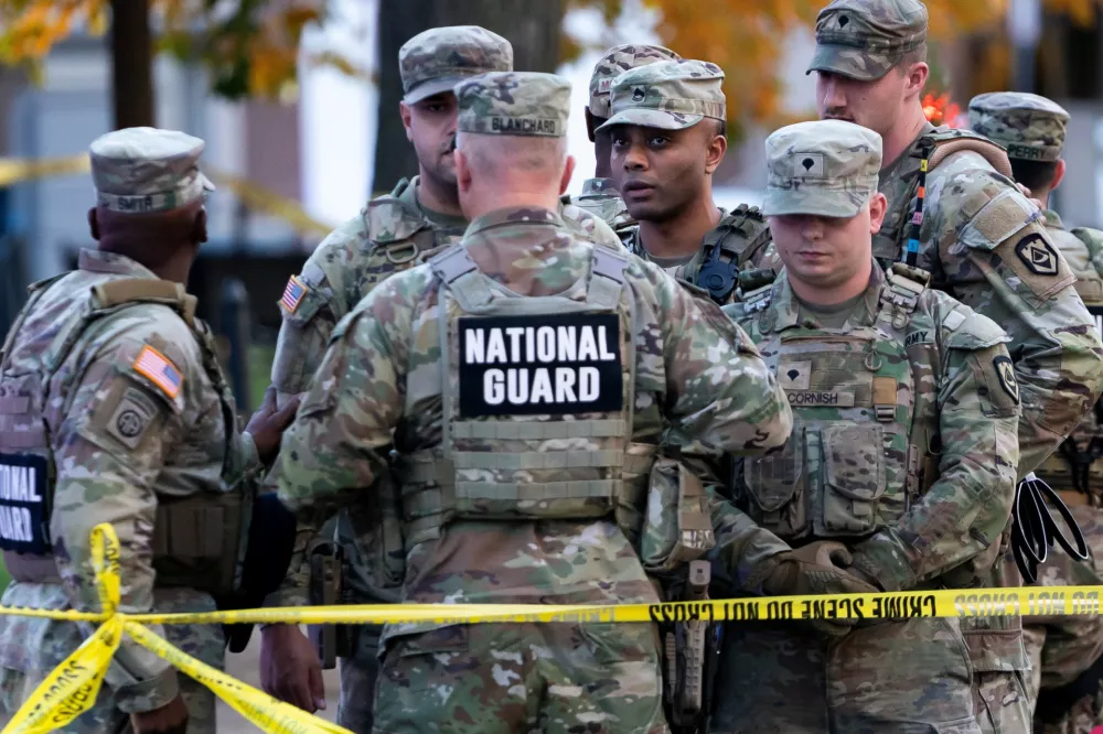 National Guard members stand together behind yellow tape, after two National Guard members were shot near the White House in Washington, D.C., U.S., November 26, 2025. REUTERS/Nathan Howard