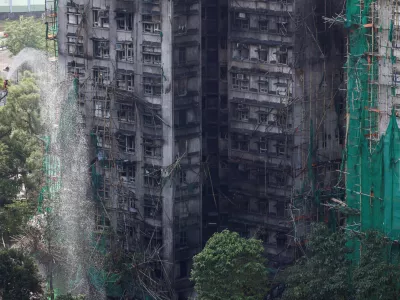 A firefighter works in front of the multiple charred buildings of Wang Fuk Court complex following a deadly fire, in Tai Po, Hong Kong, China, November 28, 2025. REUTERS/Tyrone Siu housing estate,