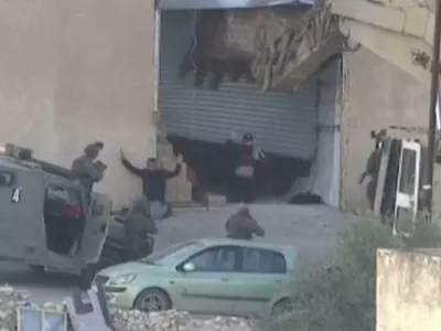 This image taken from video by Palestine TV shows two Palestinian men kneeling on the ground to Israeli forces shortly before they were shot dead during a military operation in Jenin, West Bank, on Thursday, Nov. 27, 2025. (Palestine TV via AP)
