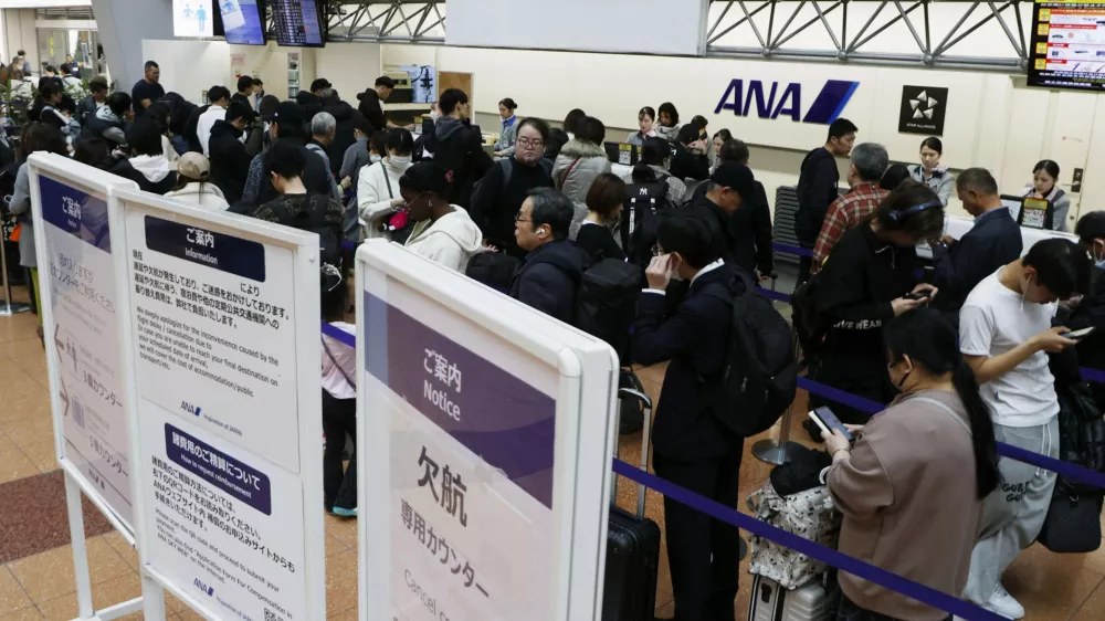 Passengers wait in line at All Nippon Airways' counter at Haneda airport in Tokyo Saturday, Nov. 29, 2025. A sign, right, reads " Flight cancellation counter." (Takahiko Kanbara/Kyodo News via AP)