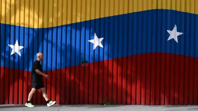A man walks past a mural with the colors of the Venezuelan flag, after U.S. President Donald Trump said on Saturday that the airspace above and around Venezuela would be completely closed, amid rising tensions between the Trump administration and the government of Venezuelan President Nicolas Maduro, in Caracas, Venezuela, November 29, 2025. REUTERS/Gaby Oraa
