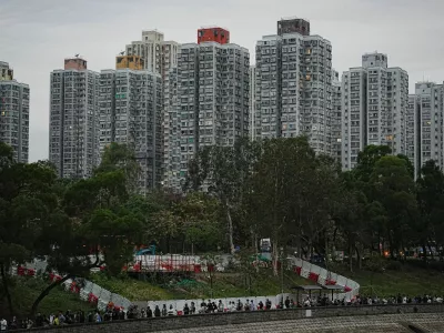 People queue to place flowers at a makeshift memorial near Wang Fuk Court housing estate to pay tribute to victims of the deadly fire at the Wang Fuk Court housing complex, in Tai Po, Hong Kong, China, November 30, 2025. REUTERS/Lam Yik