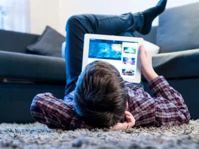 teenager with tablet while lying on the floor in the room