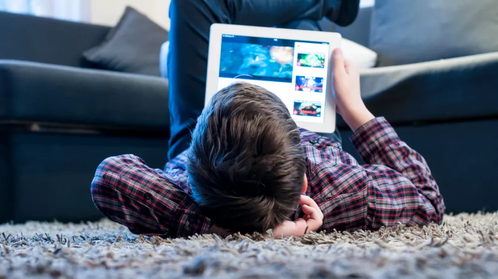 teenager with tablet while lying on the floor in the room