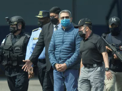 FILE PHOTO: Honduras former President Juan Orlando Hernandez is escorted by authorities as he walks towards a plane of the U.S. Drug Enforcement Administration (DEA) for his extradition to the United States, to face a trial on drug trafficking and arms possession charges, at the Hernan Acosta Mejia Air Force base in Tegucigalpa, Honduras April 21, 2022. REUTERS/Fredy Rodriguez/File Photo