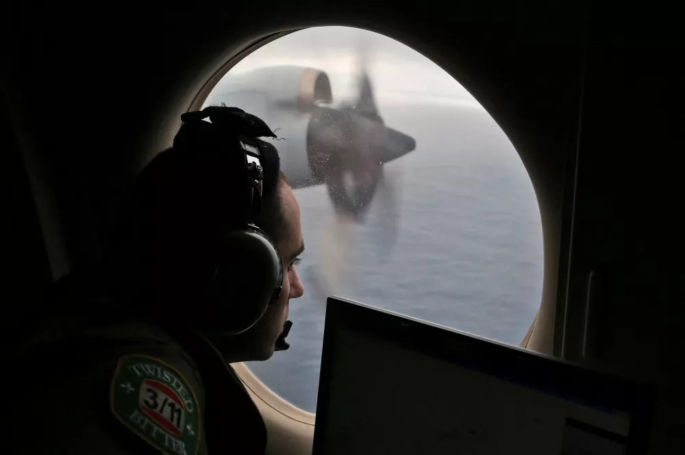 FILE - Flight officer Rayan Gharazeddine scans the water in the southern Indian Ocean off Australia from a Royal Australian Air Force AP-3C Orion during a search for the missing Malaysia Airlines Flight MH370 on March 22, 2014. (AP Photo/Rob Griffith, File)wld