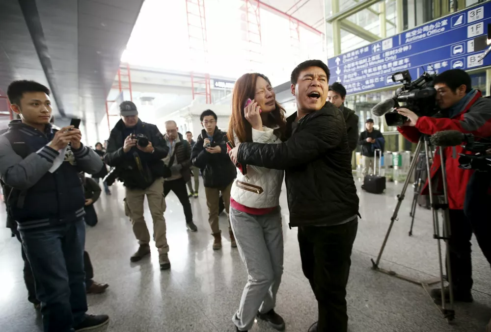A relative (woman in white) of a passenger onboard Malaysia Airlines flight MH370 cries as she talks on her mobile phone at the Beijing Capital International Airport in Beijing in this March 8, 2014 file photo. Malaysia is "almost certain" that plane debris found on Reunion Island in the Indian Ocean is from a Boeing 777, the deputy transport minister said on July 30, 2015, heightening the possibility it could be wreckage from missing Flight MH370. REUTERS/Kim Kyung-Hoon/Files