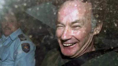 FILE - In this Nov. 4, 1997, file photo, Ivan Milat smiles in a police car after attending a court in Sydney, Australia. Milat, whose grisly serial killings of young backpackers horrified Australians in the early '90s, died in a Sydney prison on Sunday, Oct. 27, 2019, prison authorities said. He was 74. (AP Photo/Rick Rycroft, File)