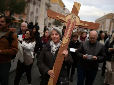 A pilgrim carries a cross near Saint Peter's Square, after a high-level Vatican commission voted against allowing Catholic women to serve as deacons, maintaining the global Church's practice of all-male clergy, according to a report given to Pope Leo and released on Thursday, near the Vatican, in Rome, Italy, December 4, 2025. REUTERS/Guglielmo Mangiapane   TPX IMAGES OF THE DAY