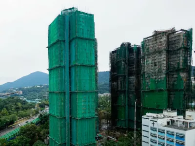 Wang Chi House, the only building not directly affected by the deadly fire at Wang Fuk Court housing complex, stands covered by protective netting, as residents return to the site to fetch their belongings, in Tai Po, Hong Kong, China December 3, 2025. REUTERS/Maxim Shemetov