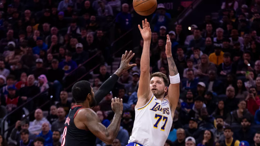 Los Angeles Lakers' Luka Doncic, right, shoots the ball against Philadelphia 76ers' Paul George, left, during the first half of an NBA basketball game, Sunday, Dec. 7, 2025, in Philadelphia. (AP Photo/Chris Szagola)