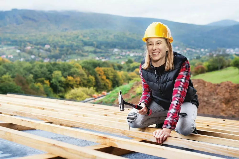 Female worker on the building site. Young woman working as a roofer. House construction. / Foto: Halfpoint