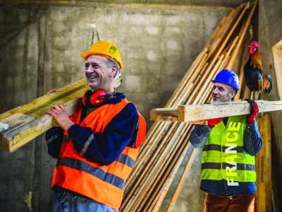 Two construction workers carrying a scaffolding at a building site - people at work concepts / Foto: Jovanmandic