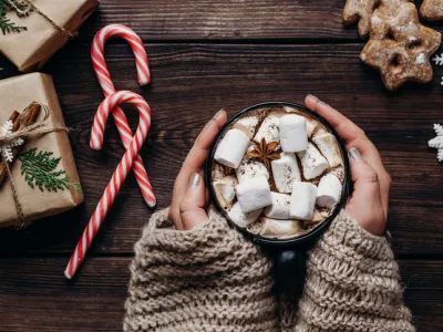 Warming concept. Woman hands in knitted sweater with mug of hot chocolate. Coziness, home, winter holidays celebration
