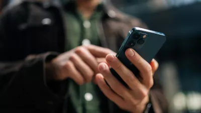 Close-up hands of unrecognizable man holding and using smartphone standing on city street, browsing internet, checking social media, using mobile application. Concept of modern communication.