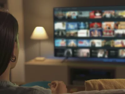 Young woman relaxing on the couch at home and watching videos on demand on her TV, entertainment concept