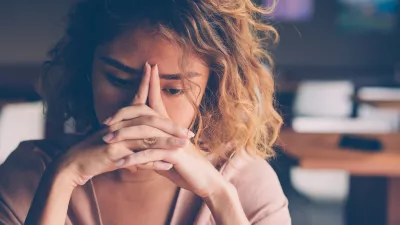 Closeup of sad young Asian woman at cafe leaning head on clasped hands and staring into vacancy. Tired freelancer feeling burnout. Stress and bad news concept / Foto: Mangostar_studio